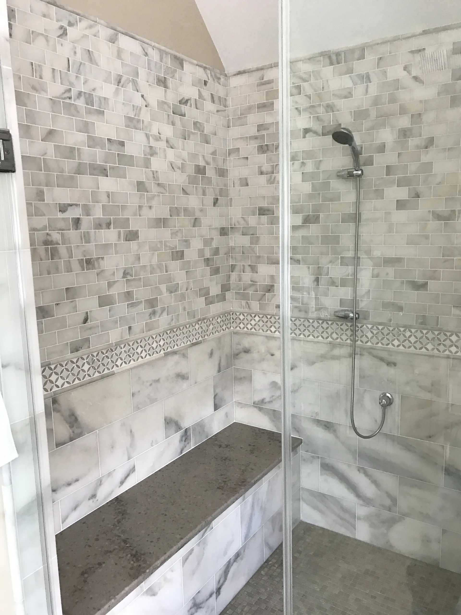 Master Bath - Main view of modern walk-in shower with horizontal accent line, calacatta tile, bench seat, shelves