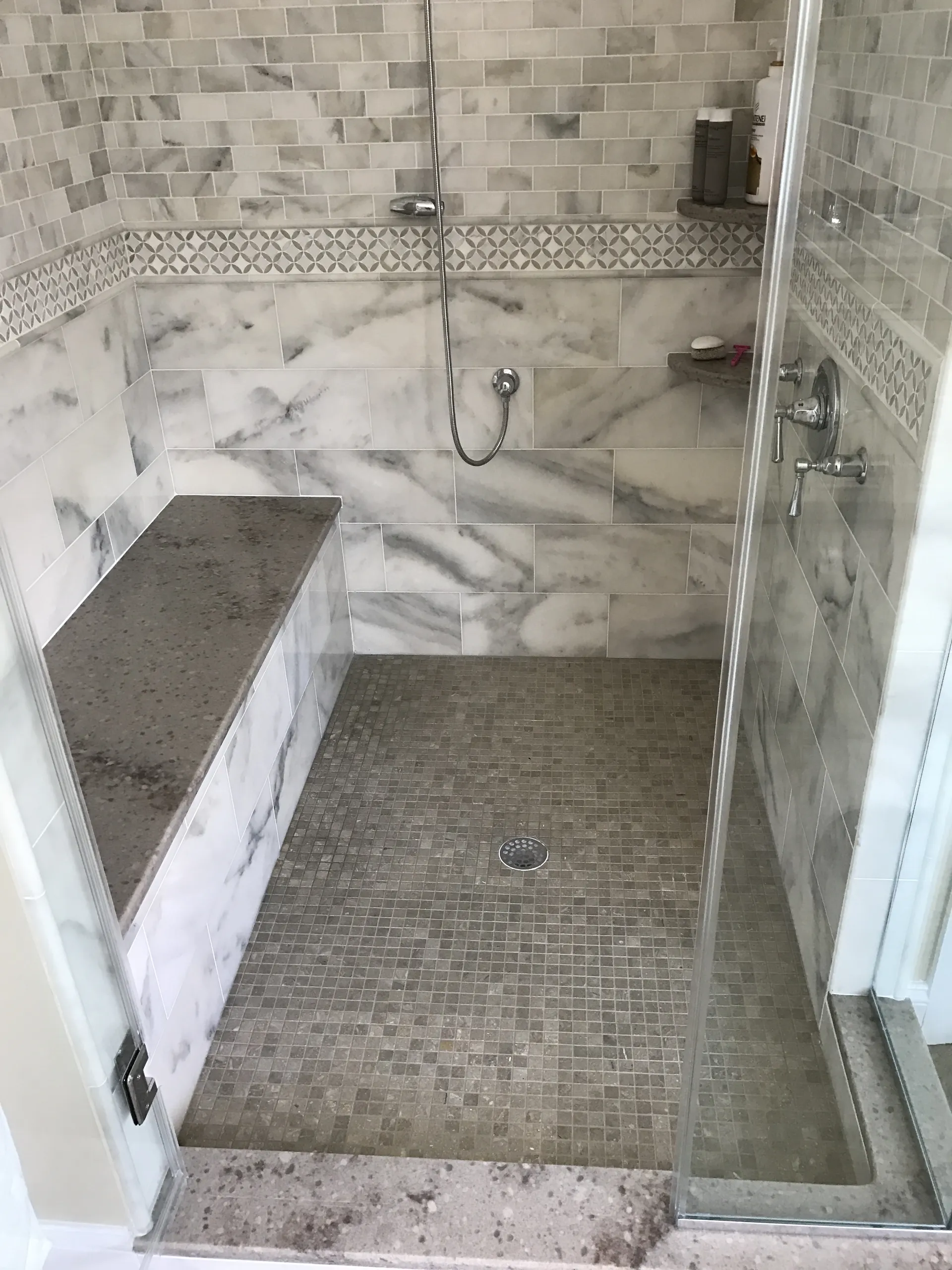 Master Bath - shower pan view of modern walk-in shower with horizontal accent line, calacatta tile, bench seat, shelves