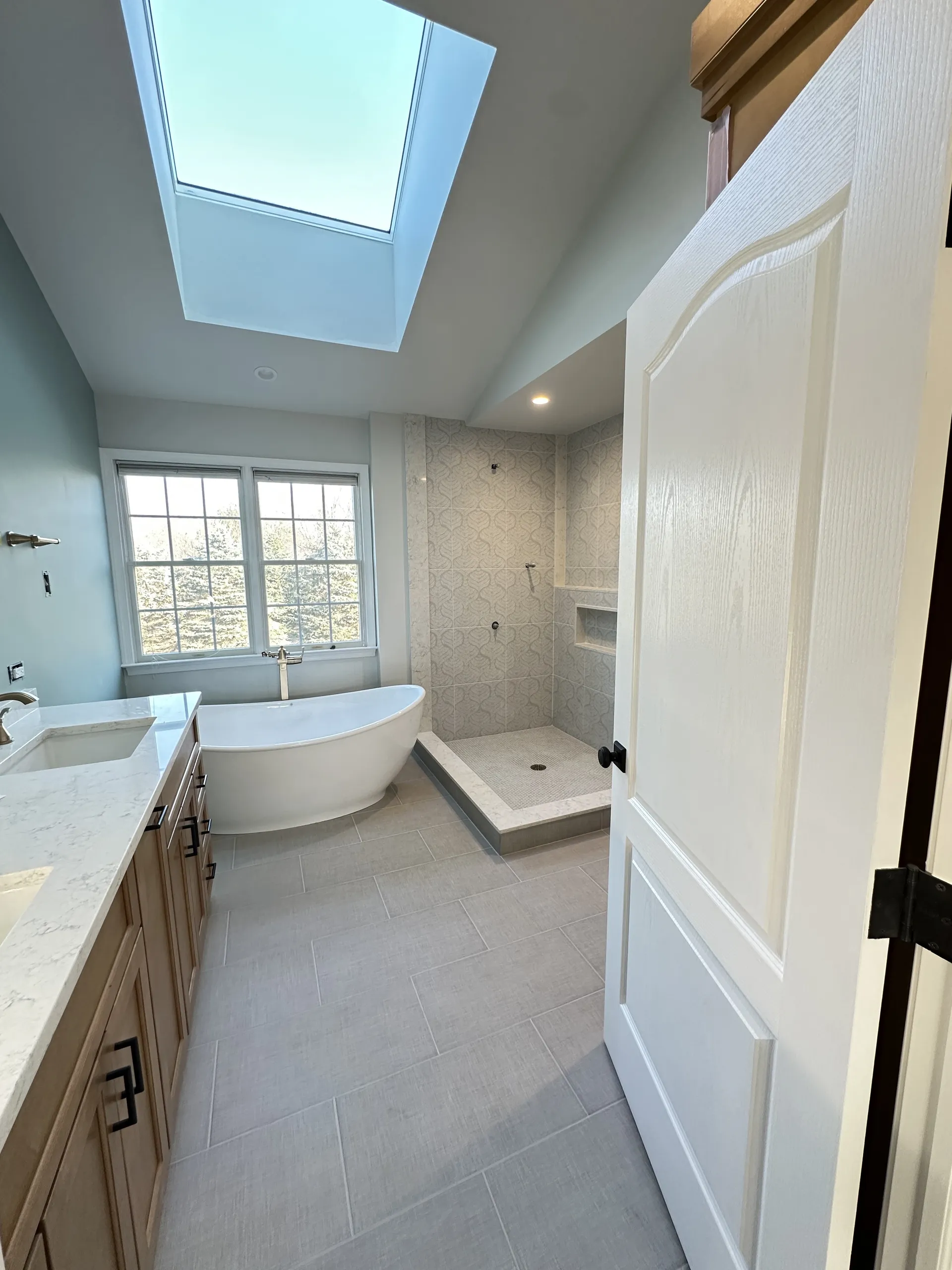 Master Bath - Full bathroom with freestanding tub and walk-in shower before glass door install, shower bump-out with ledge, marble edge panels