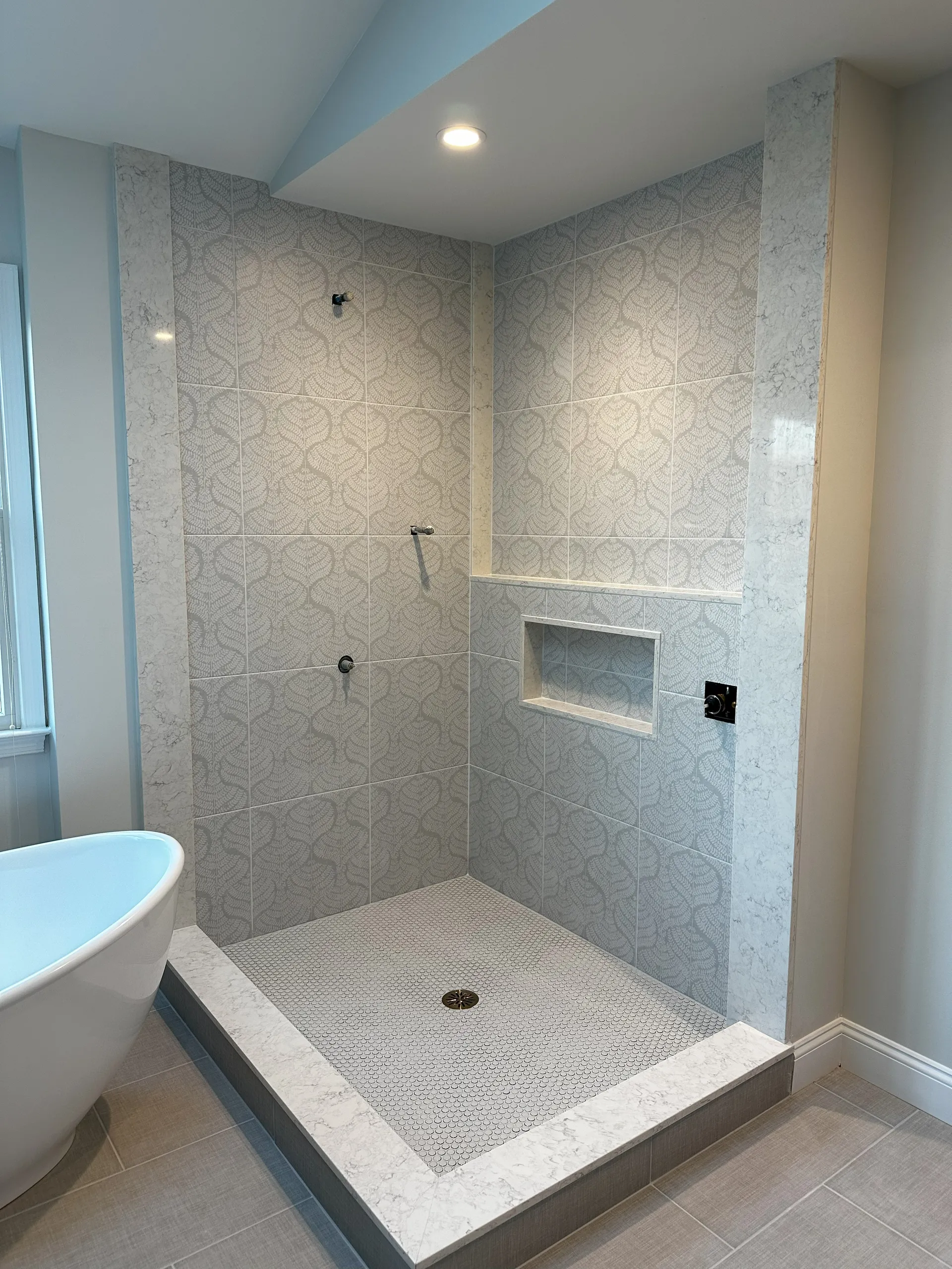 Master Bath - Full bathroom close-up view of walk-in shower before glass door install, shower bump-out with ledge, marble edge panels