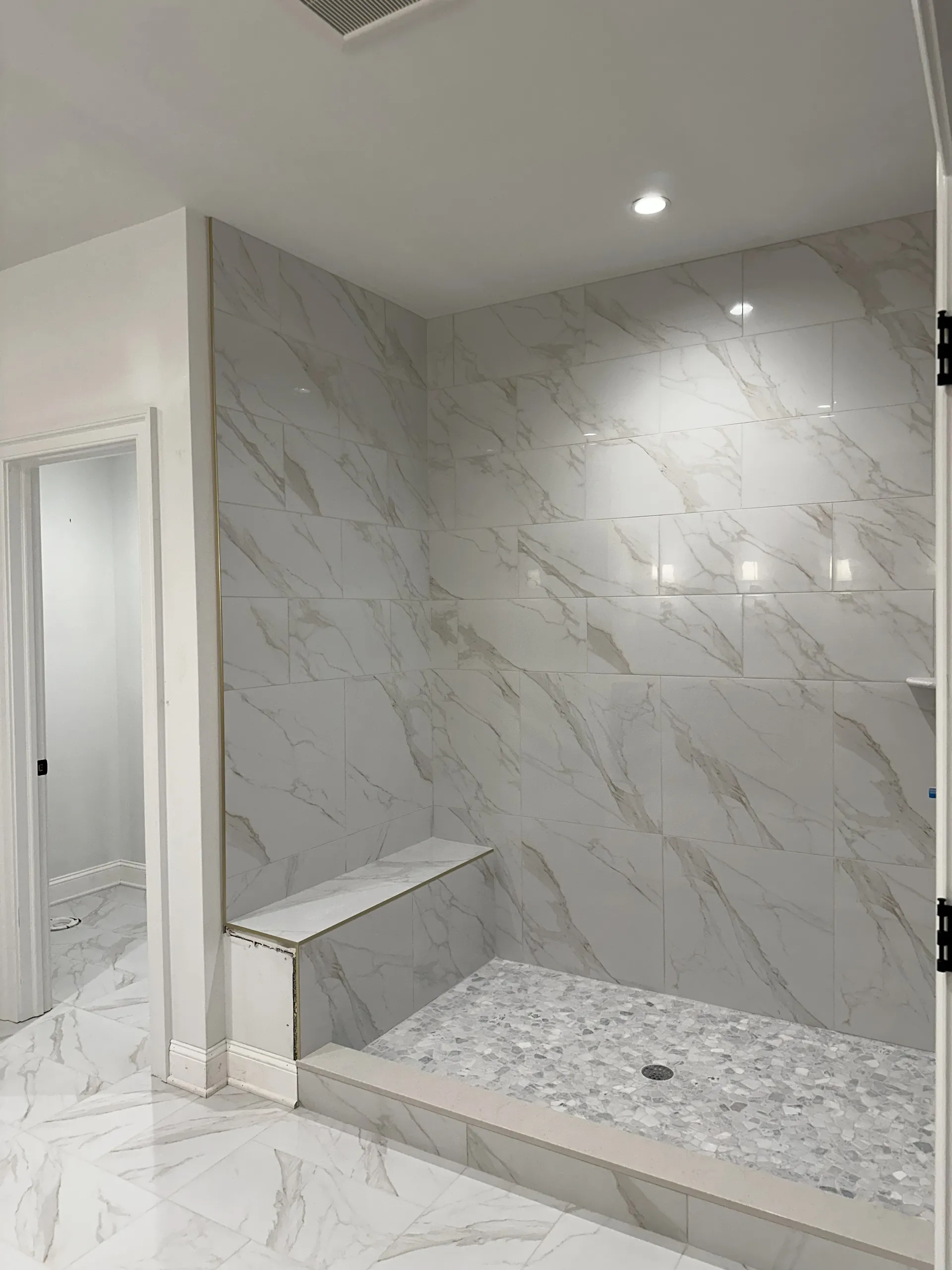Master Bath - Complete shower view showing oversized and large-format wall-tile, shower bench, and heated floors